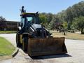 2013 John Deere 710K backhoe loader with a large front bucket positioned on a paved surface
