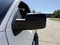 A close-up of the side mirror of a white 2014 Ford F-150 showing its angular design and reflective surface