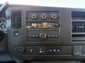 The dashboard of a 2024 Chevrolet Express features a central audio system with buttons and dials for controls as well as a digital clock display