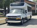 A white 2020 Chevrolet Express with a large passenger window and a low-step entrance, displaying a prominent Chevrolet logo on the front grille