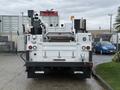 A 2018 Ford F-550 utility truck is shown from the rear featuring truck bed storage compartments and a mounted crane on top with various tools and equipment
