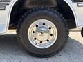 A close-up of a silver wheel rim with a shiny chrome finish mounted on a large black off-road tire with visible tread and the brand name Goodyear and Wrangler printed on it
