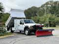A 2007 Ford F-450 truck with a large silver dump bed and a red snow plow attached to the front