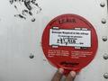 A red circular sticker with text indicating a mileage retorque requirement for a vehicle, with a handwritten distance of 194,928 km and date of 1/12/13
