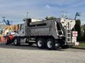 A 2013 Freightliner 114SD dump truck with a snow plow attached to the front and a metal dump bed in the rear