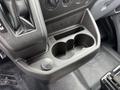 A close-up view of the center console of a 2017 Ford Transit featuring a cup holder and a 12V power outlet