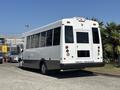 A white 2020 Chevrolet Express shuttle bus with large windows and rear door, parked in a lot with a message on the back that says please yield thanks for the ride