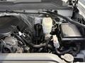 Engine compartment of a 2016 Chevrolet Silverado 2500HD featuring a black engine cover alongside various hoses and components including a coolant reservoir and battery
