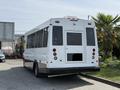 A white 2020 Chevrolet Express bus with large windows and a rear door is parked with its back facing the viewer