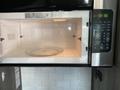 An open microwave with a glass turntable inside and a digital control panel on the right displaying the time 1256