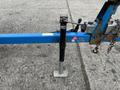 A 2016 Genie TZ-34/20 trailer with a blue support arm and a black adjustable jack positioned on a flat surface