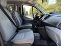 Interior of a 2016 Ford Transit 150 showing two front seats with seatbelts and a dashboard with controls and space for a center console