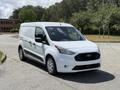 A 2021 Ford Transit Connect van in white with a black grille parked on a paved surface