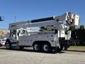 A 2013 International 7500 bucket truck with an extended boom arm and a work platform mounted on the side of its flatbed chassis