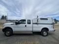 A white 2014 Ford F-350 SD pickup truck with a utility cap on the bed and a crew cab design