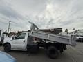 A 2004 Ford F-350 SD dump truck with a raised bed positioned to unload materials