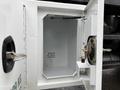 A partially open compartment of a 2020 International MV607 truck revealing a plain interior with a small shelf and a latch mechanism