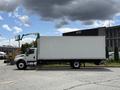 A 2022 International MV607 truck with a white cargo box and a lift arm raised on the side