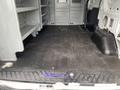 Empty interior of a 2017 Ford Transit cargo van featuring metal shelving units along one side and a rubber mat on the floor