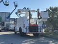 A 2006 Freightliner M2 106 utility truck with two elevated bucket arms attached for workers to access high areas