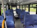 Interior of a 2020 Chevrolet Express bus with multiple blue fabric seats and a spare tire in the aisle