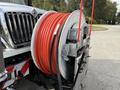Close-up of a 2014 International 7500 featuring a large spool of bright orange hose mounted on a reel with a display monitor attached