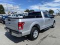 A silver 2015 Ford F-150 pickup truck with a black bed cover and chrome accents parked at a dealership