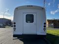 A white 2014 Ford Econoline with a large rear door and red taillights parked on the street