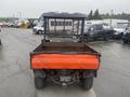 A 2010 Kubota RTV 900 utility vehicle with a black cab and an orange cargo bed viewed from the rear showing its rugged tires and open cargo area