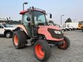 A 2010 Kubota M6040 tractor with a red and black exterior, large tires, and enclosed cab, designed for agricultural and landscaping tasks
