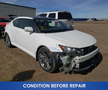 A damaged white 2013 Scion TC with a missing front bumper and visible bodywork damage in the foreground