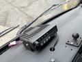 A black radio device with multiple buttons sits on the dashboard of a vehicle