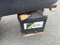 A close-up of the battery of a 2009 John Deere 2653B Precision showing a black battery case with a label that reads Hub Power and a connected cable