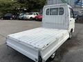 A 2010 Daihatsu Hijet in white with an open cargo bed and a compact design featuring a closed cabin and rear windows