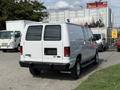 A white 2013 Ford Econoline van with a rear view showing its sliding door and windows