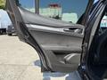 A black 2020 Alfa Romeo Stelvio with an open front door showing the interior detailing and controls on the door panel
