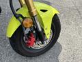 Close-up of the front wheel and brake system of a 2018 Honda Grom featuring a bright yellow fender and red brake caliper