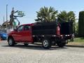 A red 2013 RAM 2500 truck with a flatbed and a black metal utility box attached to the back featuring a fire extinguisher mounted on the side