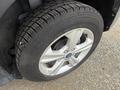 A close-up view of a silver alloy wheel and tire from a 2014 Ford Escape with distinct tread pattern and the Ford logo visible on the hubcap