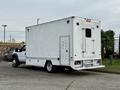 A white 2012 Ford F-550 with a large cargo box attached at the rear and various access doors on the sides