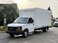 A 2015 GMC Savana box truck with a white cargo area and black front grill parked on a paved surface