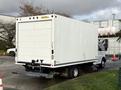 A white 2015 GMC Savana cargo van with a large boxy cargo area and a towing hitch attached to the rear
