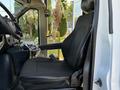 A black cloth driver's seat inside a 2014 Chevrolet Express van with an armrest and control panel beside it