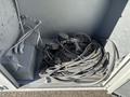A compartment containing a tangle of electrical cords and connectors alongside a gray electrical box