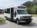 A 2017 Chevrolet Express shuttle bus with a white exterior and a black front grille parked with the door open