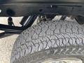 Close-up of a tire and suspension system of a 2016 GMC Sierra 1500 showing tread pattern and wheel rim details