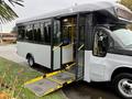 A 2019 Chevrolet Express with an open side door and a wheelchair ramp extended, displaying blue seats inside