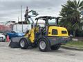 A yellow and black 2014 Wacker Neuson WL34 wheeled loader with a front bucket attachment facing to the left
