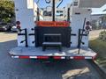 2006 Freightliner M2 106 work truck with a rear platform featuring warning signage for frequent stops and various equipment mounting points