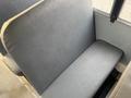 A gray vinyl seat with a flat cushion, commonly found in buses, showing minimal wear and a simple design without any visible markings